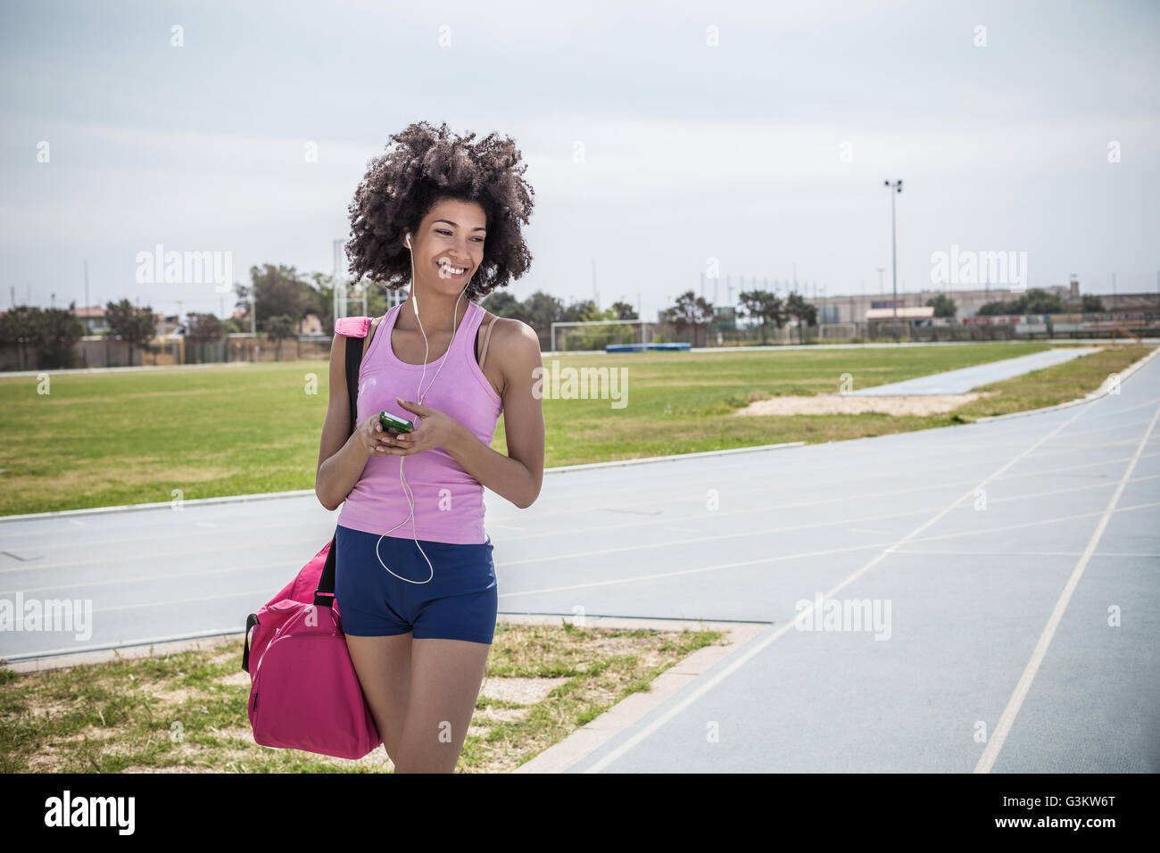 Junge Frau, training, Kopfhörer auf Laufstrecke anhören Stockfoto