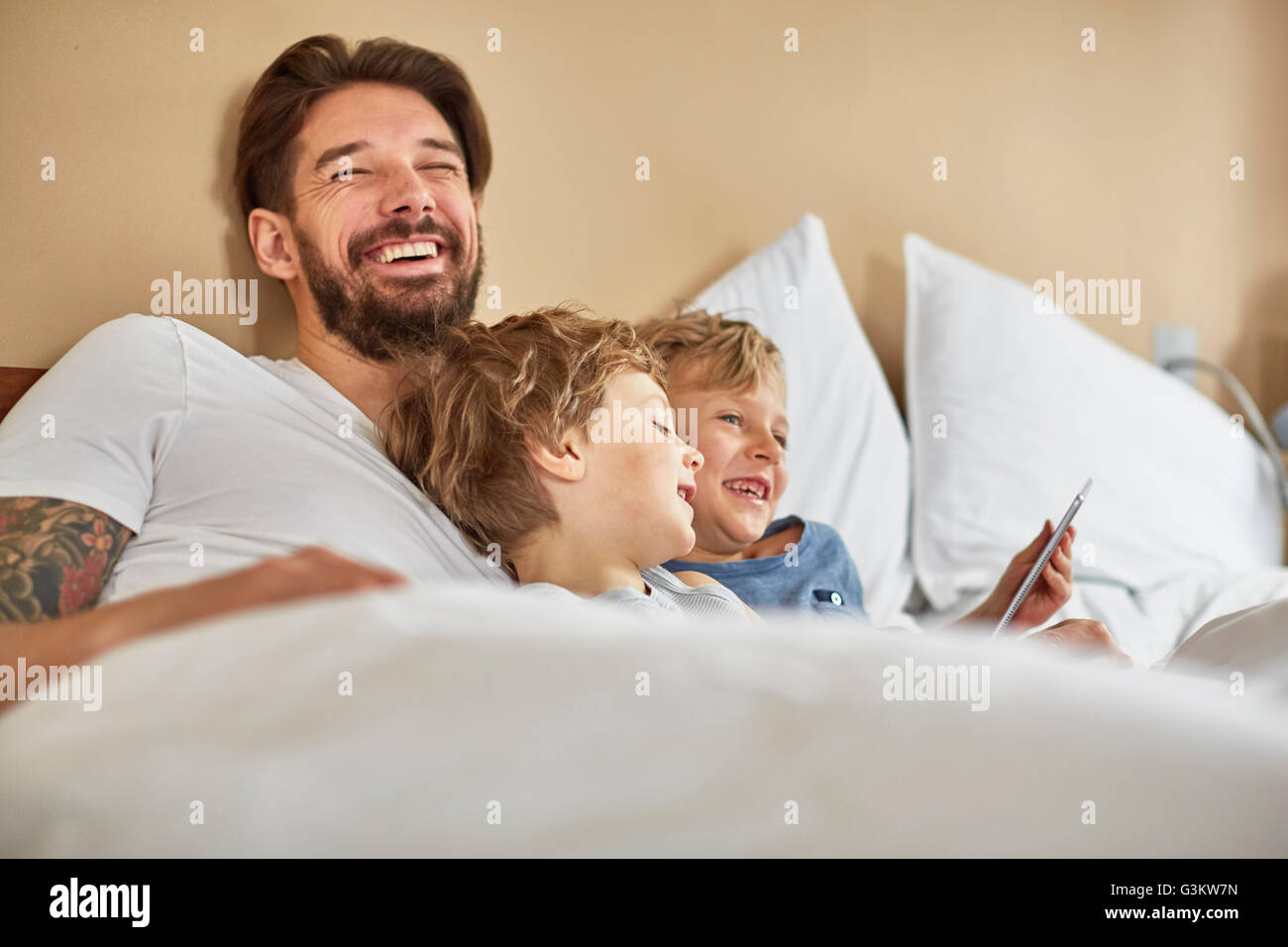 Vater und Söhne im Bett mit digital-Tablette zu lachen Stockfoto Vater und Söhne im Bett mit digital-Tablette zu lachen Stockfoto