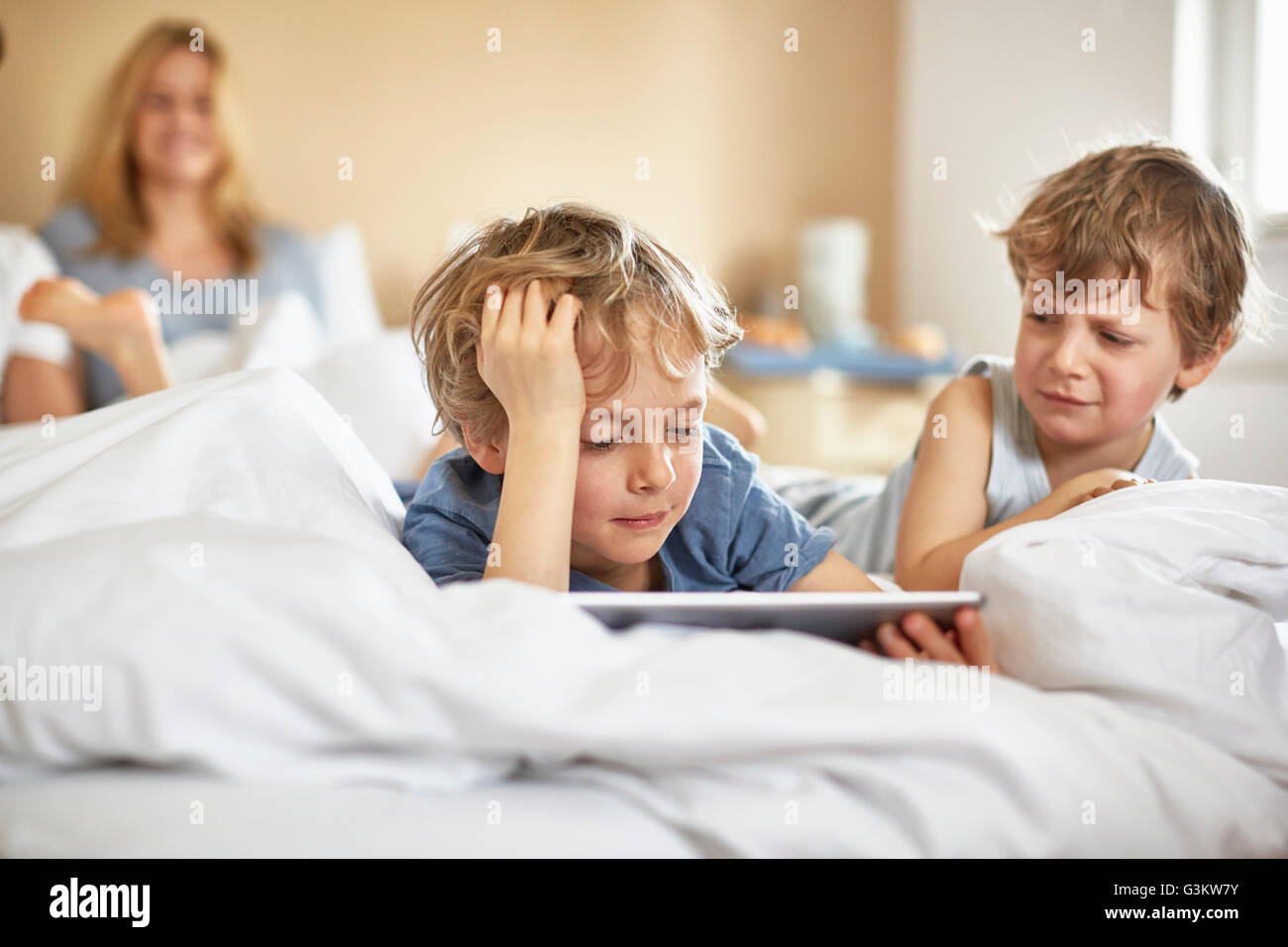 Jungs im Bett der Eltern mit digital-Tablette Stockfoto