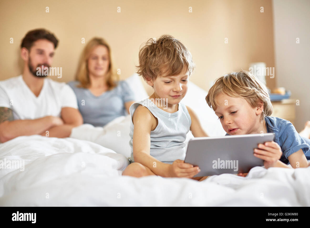 Jungs im Bett der Eltern mit digital-Tablette Stockfoto