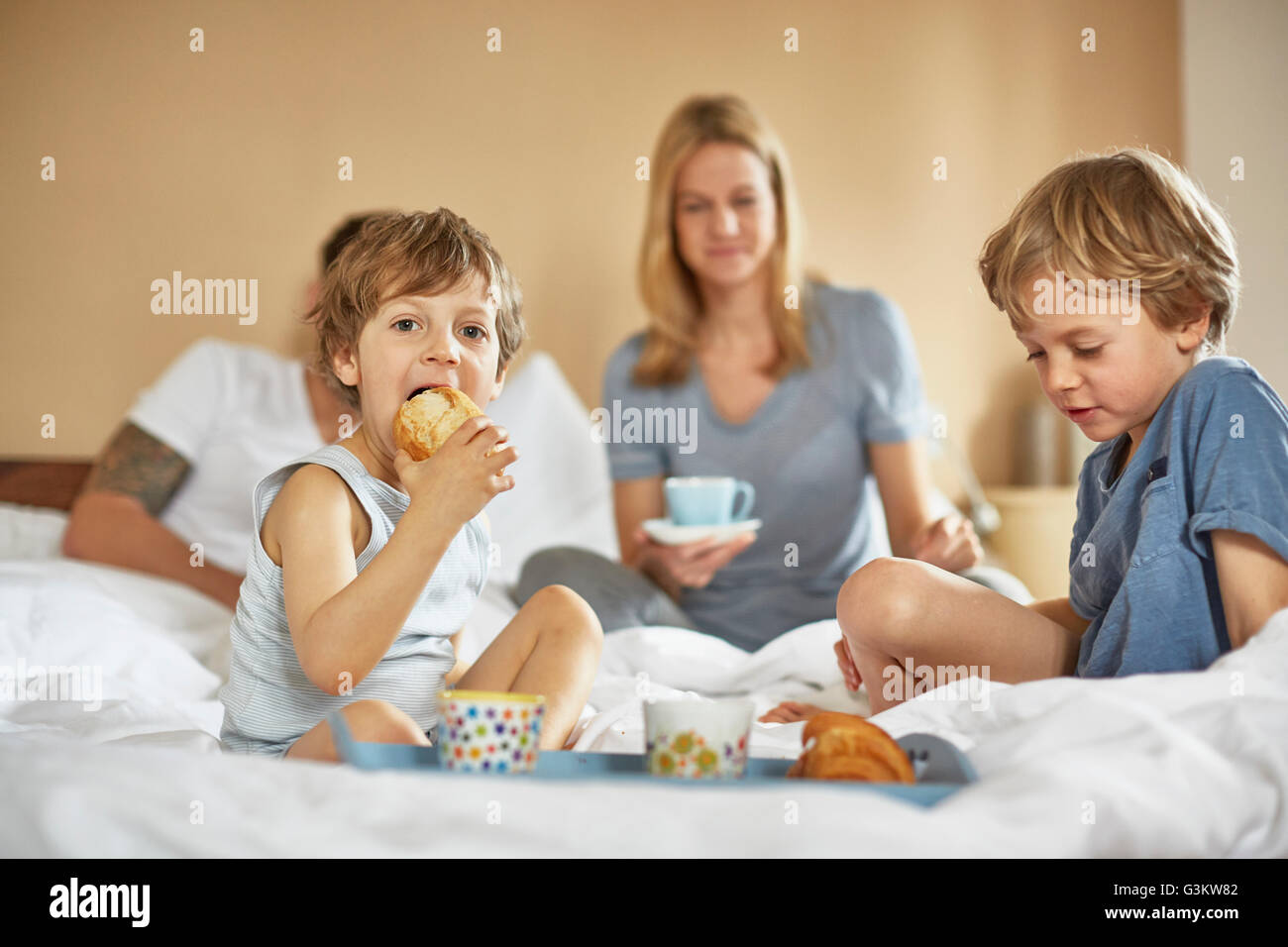 Jungen mit Frühstück im Bett der Eltern Stockfoto