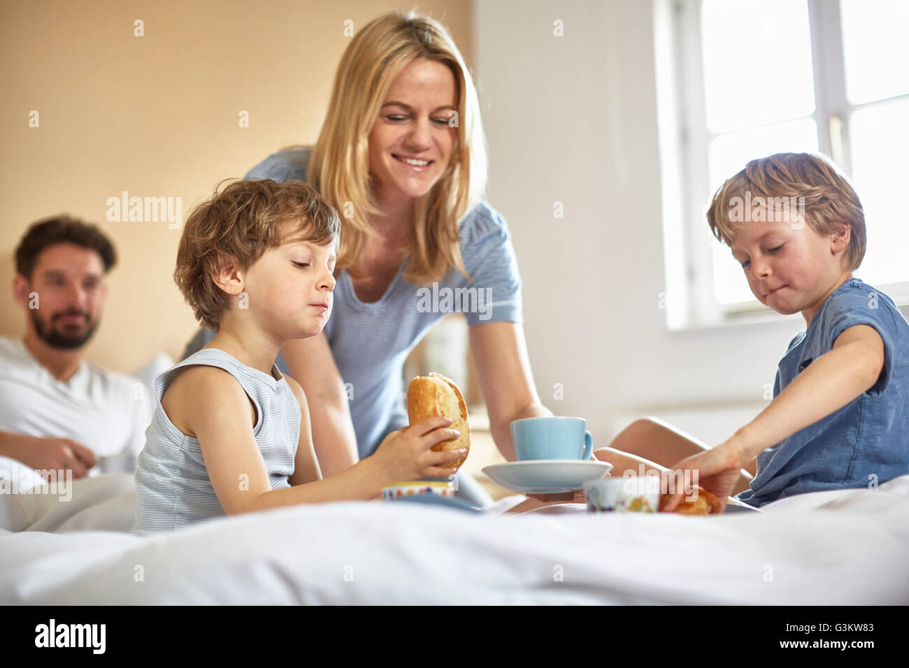 Jungen mit Frühstück im Bett der Eltern Stockfoto