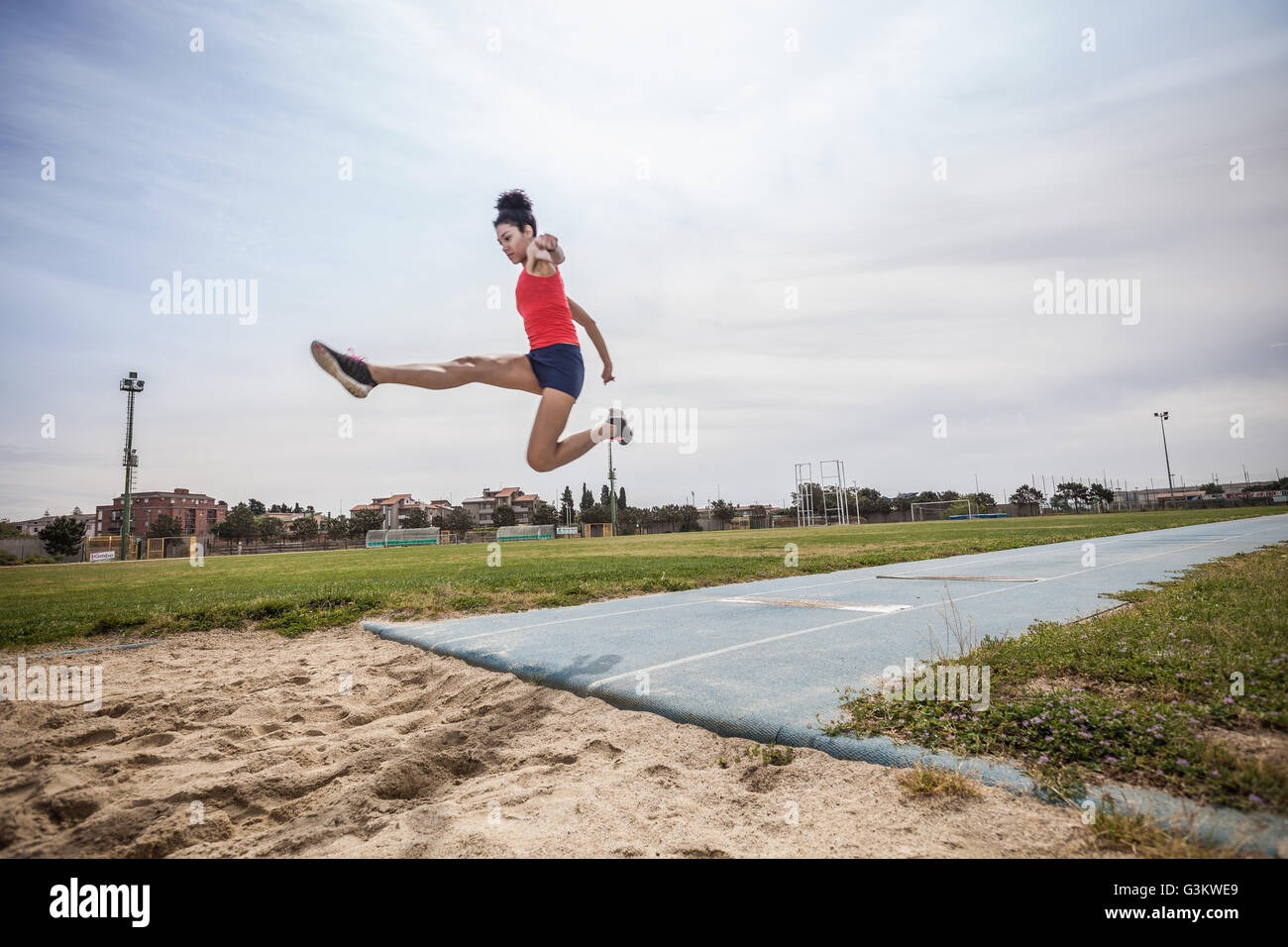 Junge weibliche Weitspringer springen Luft bei Sportanlage Stockfoto