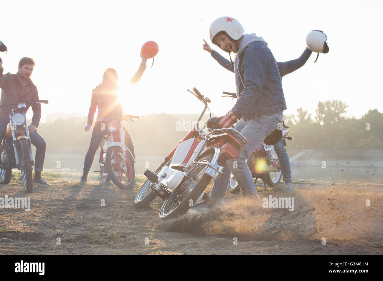 Kleine Gruppe von Freunden auf Mopeds, sitzen mit Sturzhelmen in Luft Stockfoto