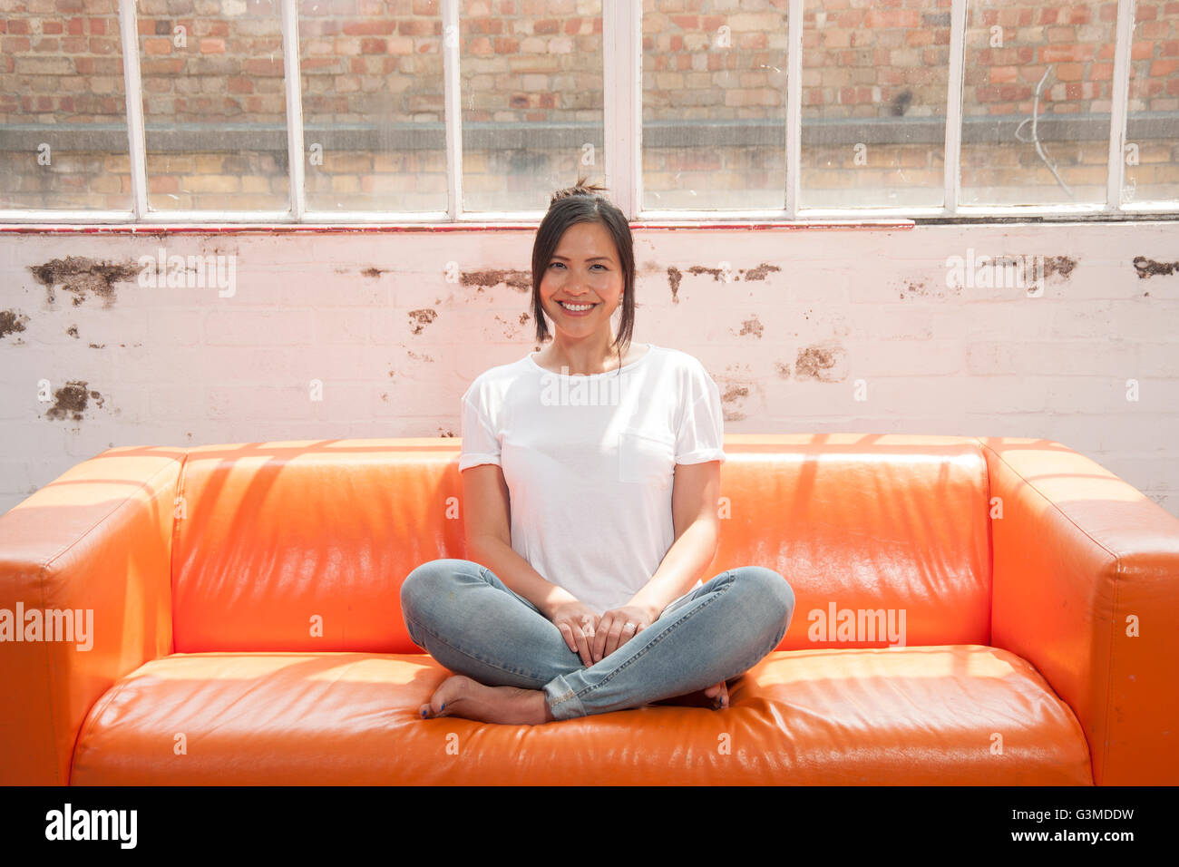 Frau sitzt auf dem Sofa entspannen und lächelnd vierbeinigen gekreuzt Stockfoto
