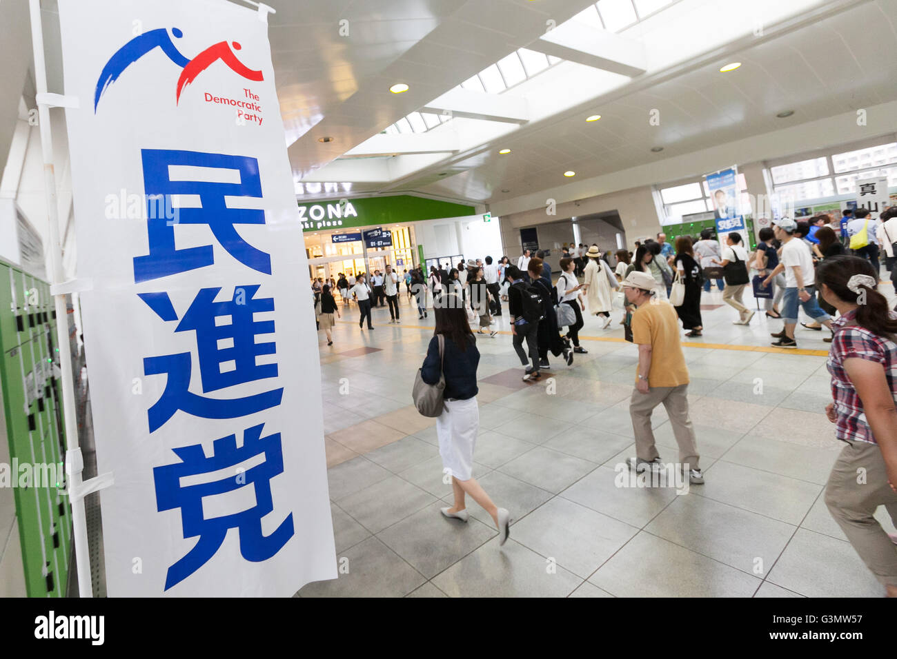 Fußgänger gehen vorbei an eine Flagge der Demokratischen Partei während einer Veranstaltung der Kampagne für Julys Oberhaus Wahlen am Eingang der Kawasaki Station am 14. Juni 2016, Kawasaki, Japan. Okada kam zur Unterstützung der Kampagne von den ehemaligen Nachrichtensprecher Yuichi Mayama und auch Yoshiko Ichikawa für die Wahlen zum Oberhaus. Bildnachweis: Rodrigo Reyes Marin/AFLO/Alamy Live-Nachrichten Stockfoto