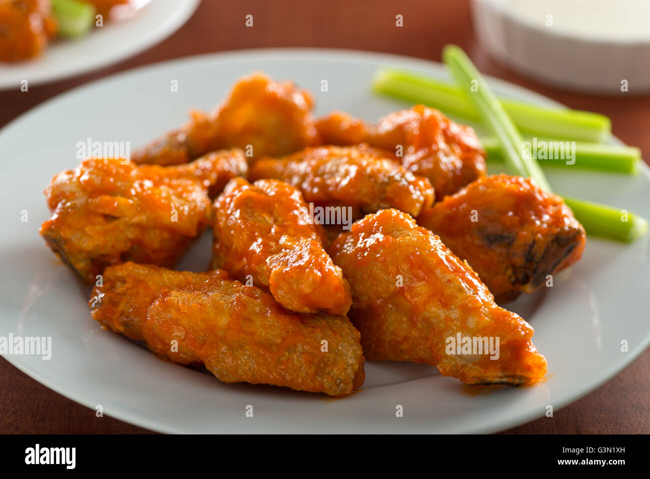 Ein Teller mit leckeren heißen würzige Hähnchenflügel mit Sriracha Sauce und Sellerie-sticks. Stockfoto