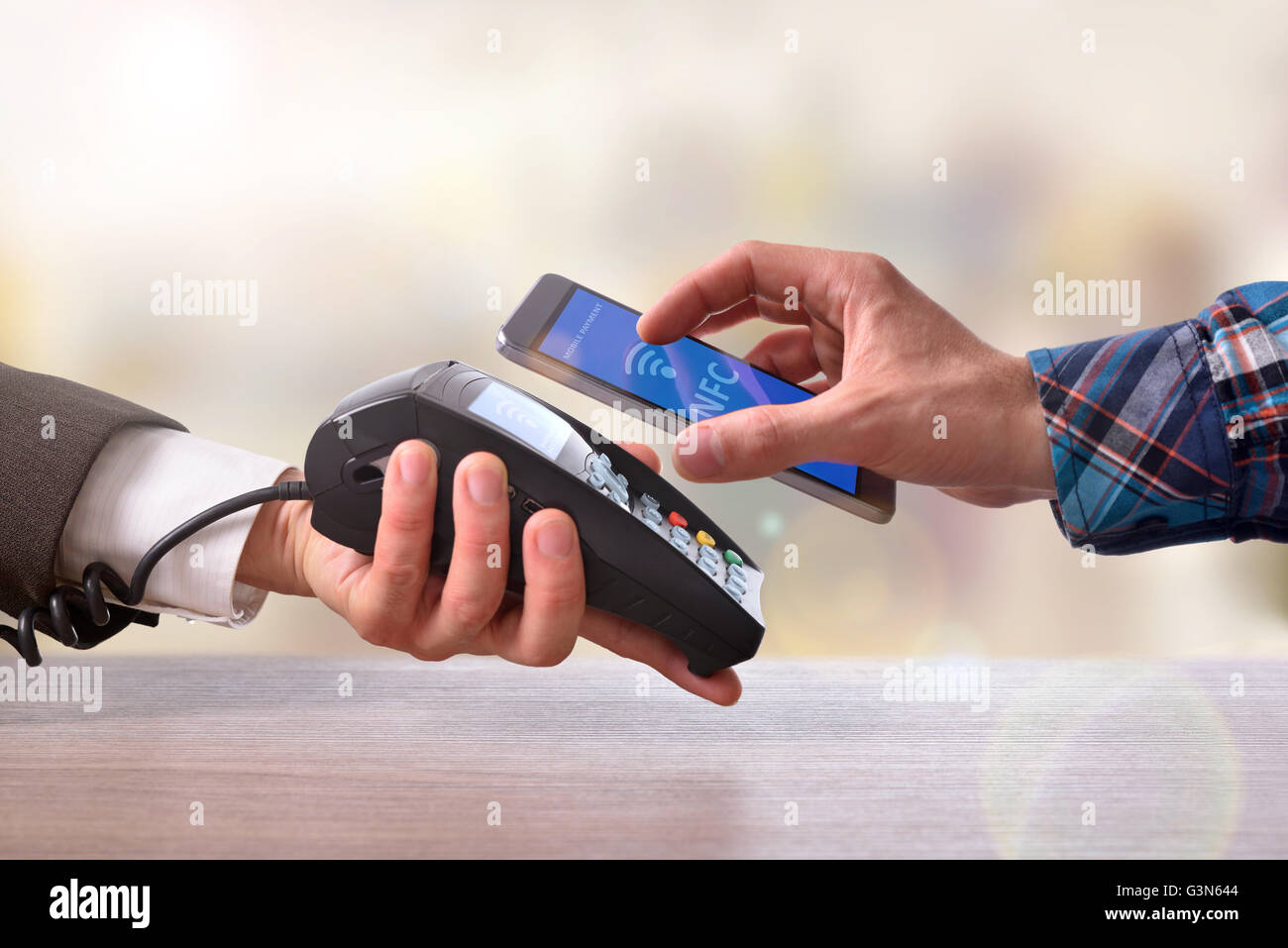 Kunden zahlen ein Kaufmann mit Handy mit NFC-Technologie. Ansicht von oben. Horizontale Komposition. Stockfoto