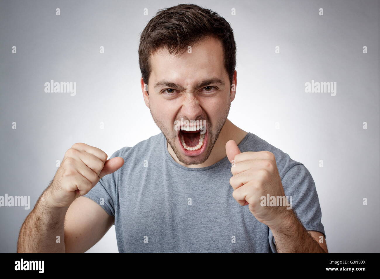 Angry Young Man Fäusten umklammert und schreien Stockfoto