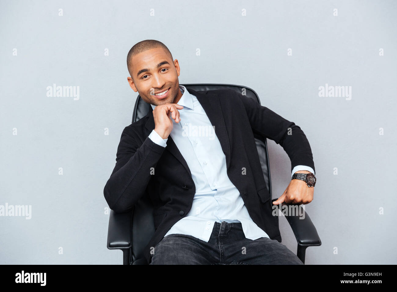 Zuversichtlich Lächeln auf den Lippen afroamerikanischen jungen Mann sitzen im Bürostuhl Stockfoto