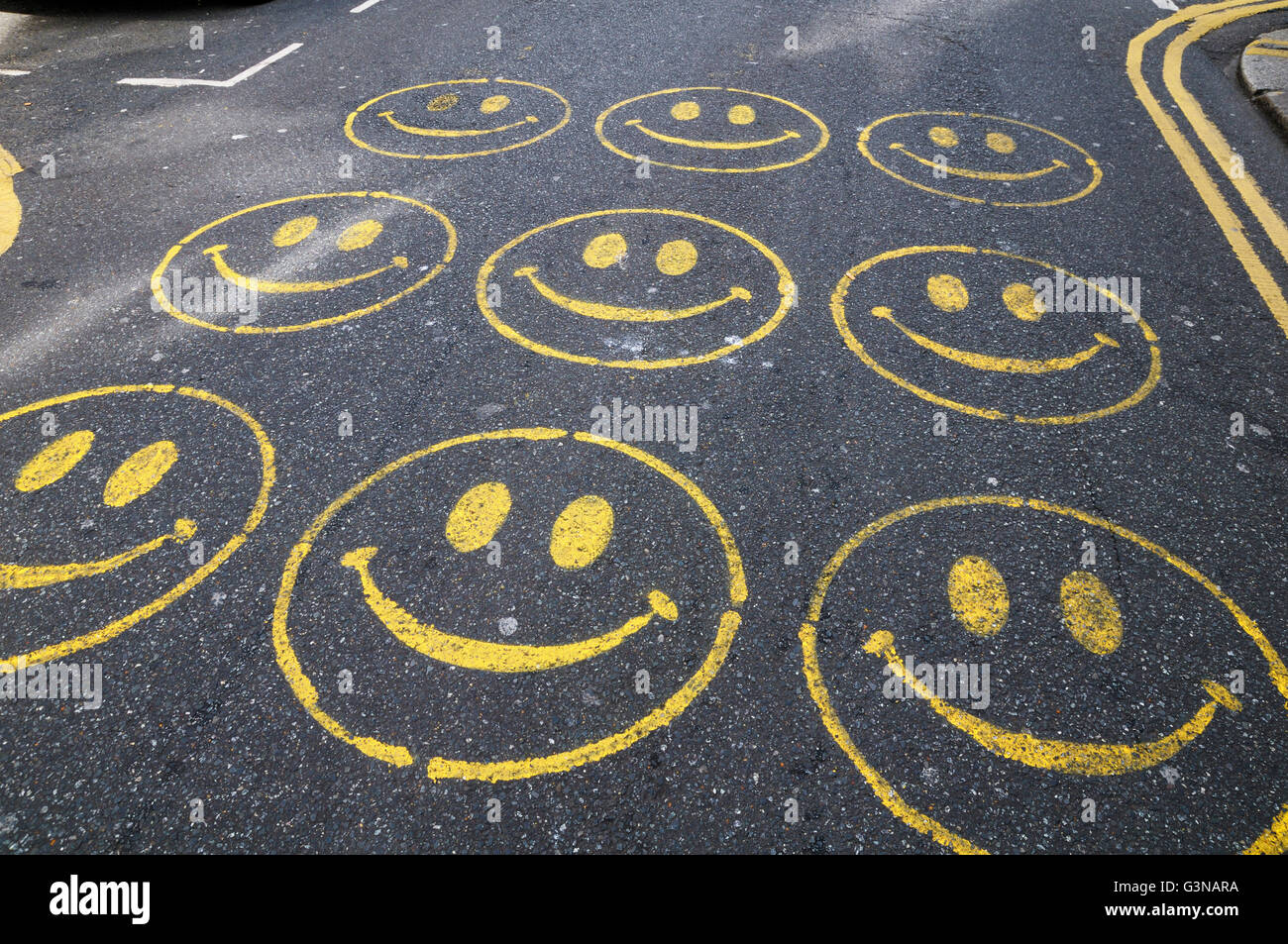 Smiley-Gesichter gemalt auf einer Straße Stockfoto