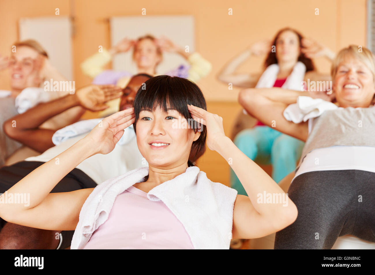 Frau macht Pilates-Übung im Unterricht zusammen mit anderen Menschen Stockfoto