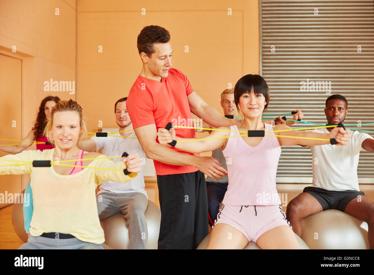 Fitness-Trainer zeigt Übung mit Band im Reha-Unterricht Stockfoto