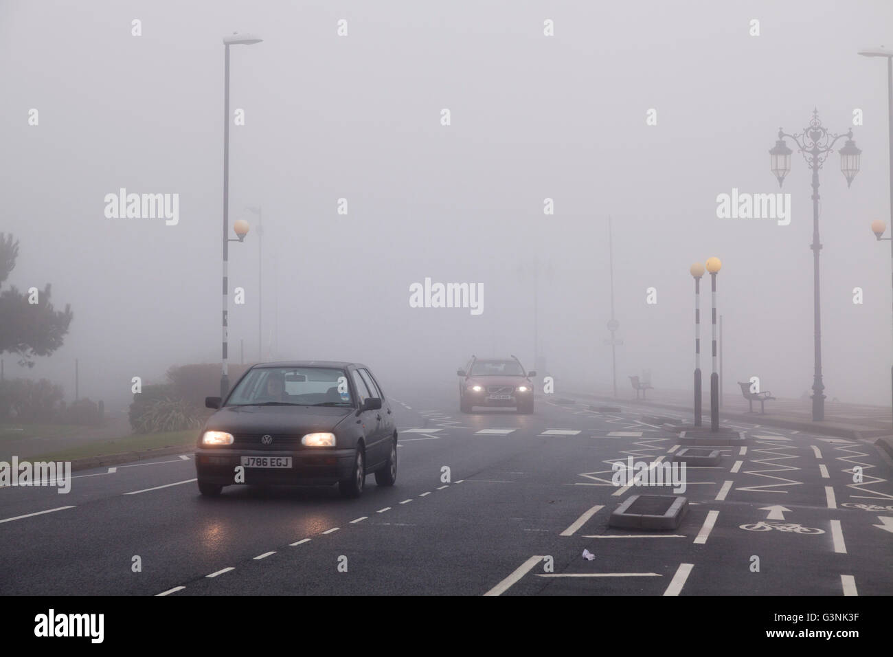 Autos Reisen im urbanen Umfeld mit Fahrbahnmarkierungen an einem nebeligen Tag mit Licht, Portsmouth, Hampshire, England Stockfoto