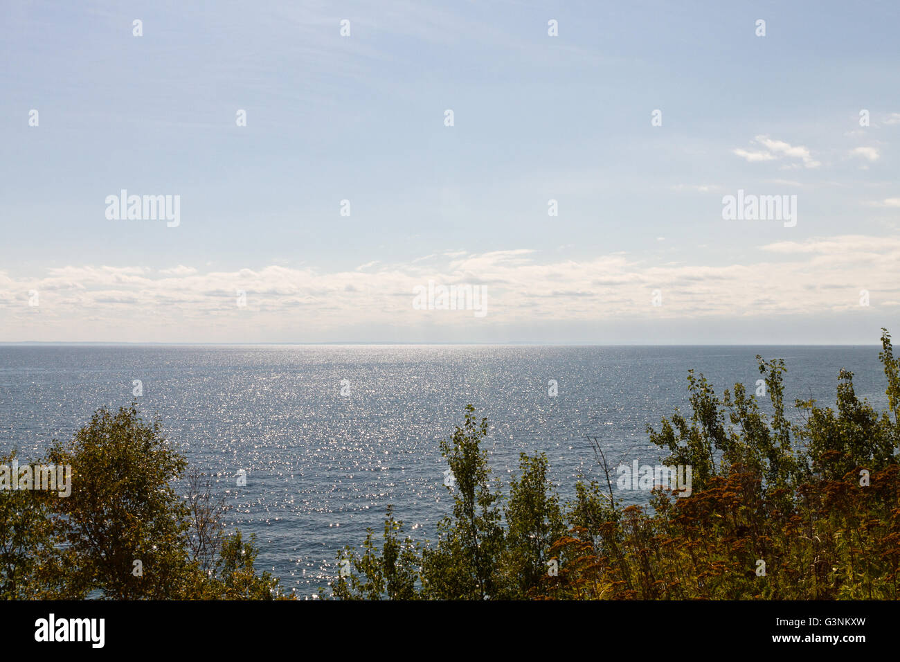 Am frühen Morgen Blick auf Lake Superior mit Wald vor und klaren blauen Wasser trifft auf den blauen Himmel am Horizont Stockfoto