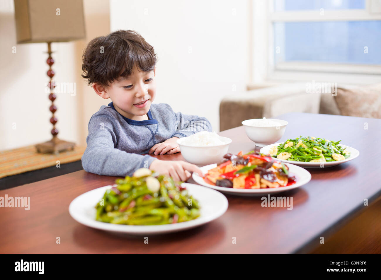 Kleiner Junge sitzt am Esstisch Stockfoto