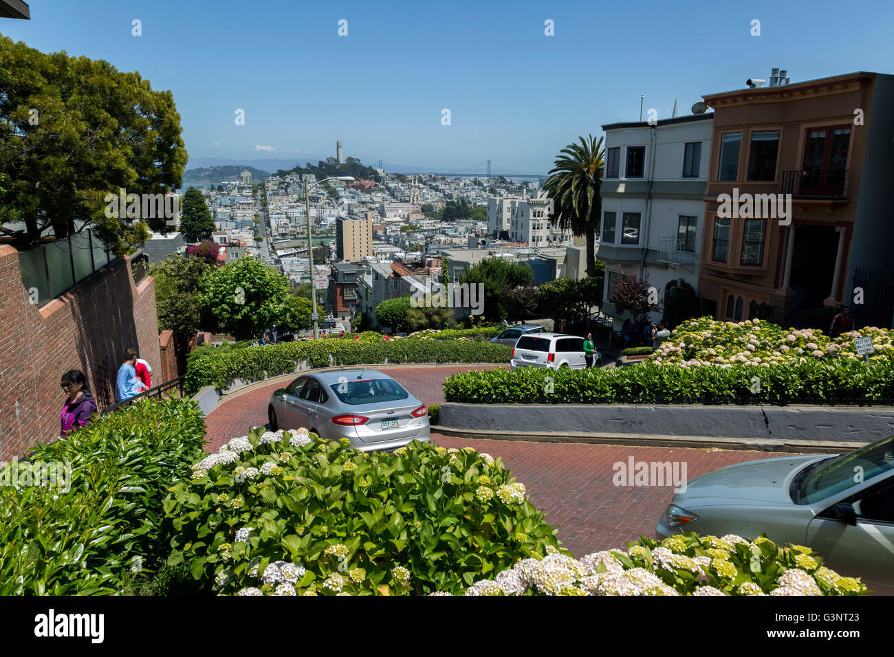 Autos, die Lombard Street in San Fransisco hinunter. Ansicht von oben mit der Stadt über. Stockfoto