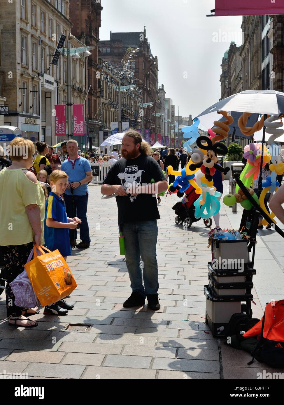 Ein Kreditor, Herstellung und Verkauf von Ballon-Figuren durch das Verdrehen von langen, bunten Luftballons auf Buchanan Street, Glasgow, Scotland, UK Stockfoto
