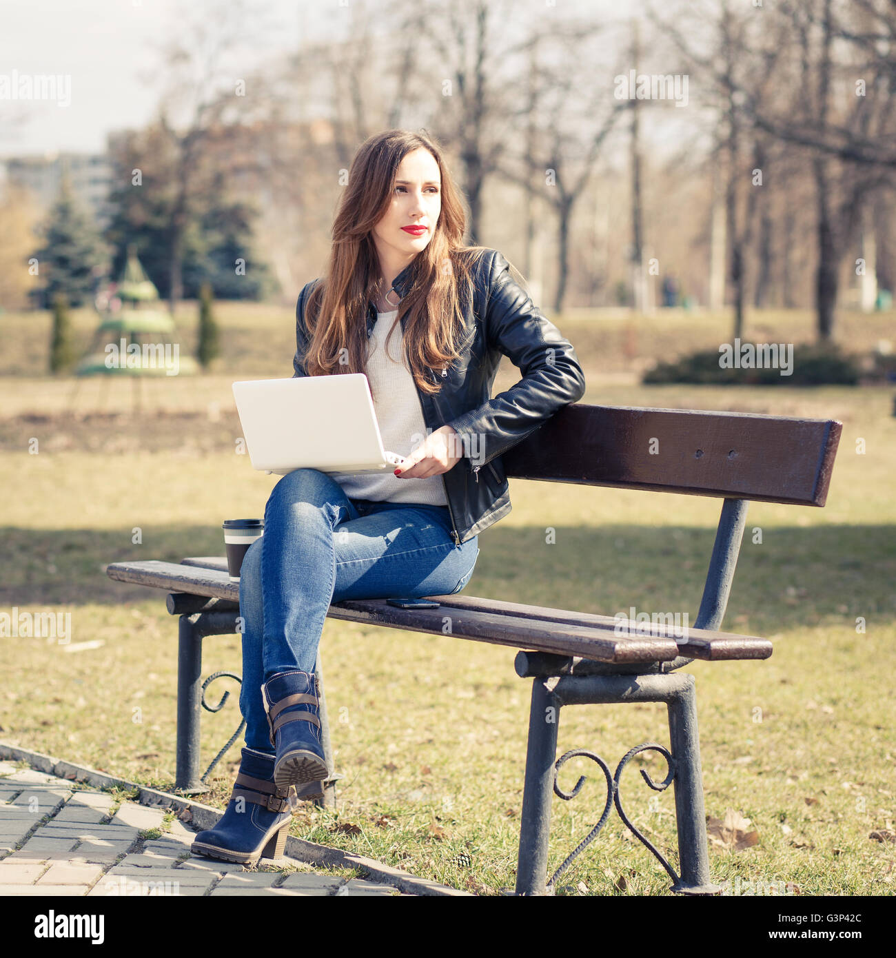 Junge Geschäftsfrau mit Laptop auf der Parkbank sitzen. Europäische lächelnd Studentin mit Notebook lesen oder lernen ich Stockfoto