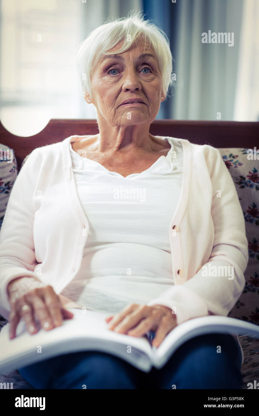 Nachdenklich blinde Frau, die mit Braille-Buch auf Schoß sitzen Stockfoto