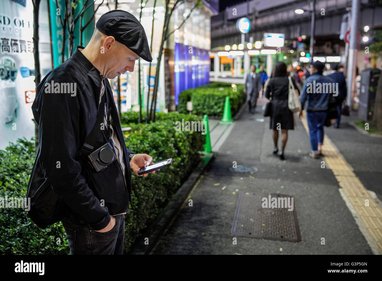 Japan, Tokio, Shibuya, Mann stehend und mit Telefon Stockfoto