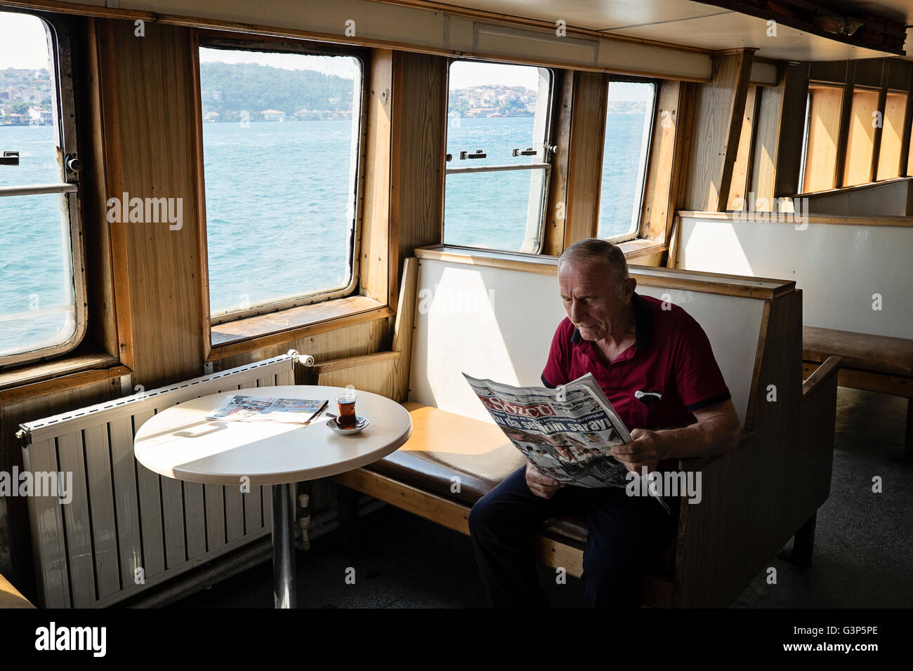 Ein Pendler liest eine Zeitung auf einer Fähre, wie es entlang des Bosporus in Istanbul, Türkei Reisen Stockfoto