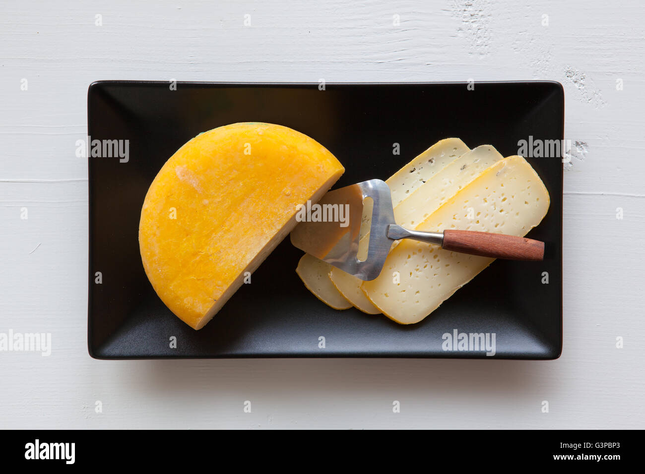 Schwarze Keramik Rechteck Gerichte mit leckeren Käse isoliert auf weißem Holz Schreibtisch Stockfoto