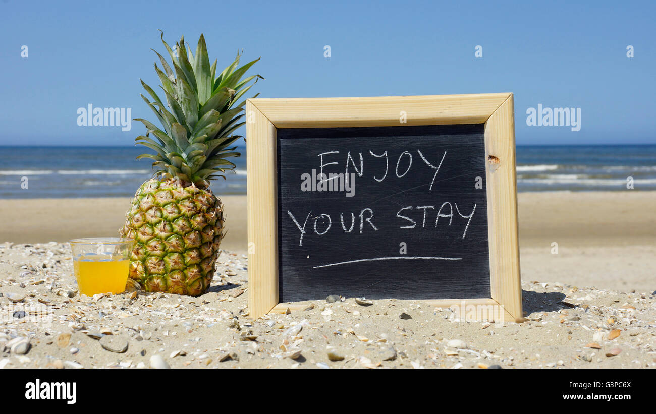 Genießen Sie Ihren Aufenthalt auf einer Tafel am Strand geschrieben Stockfoto