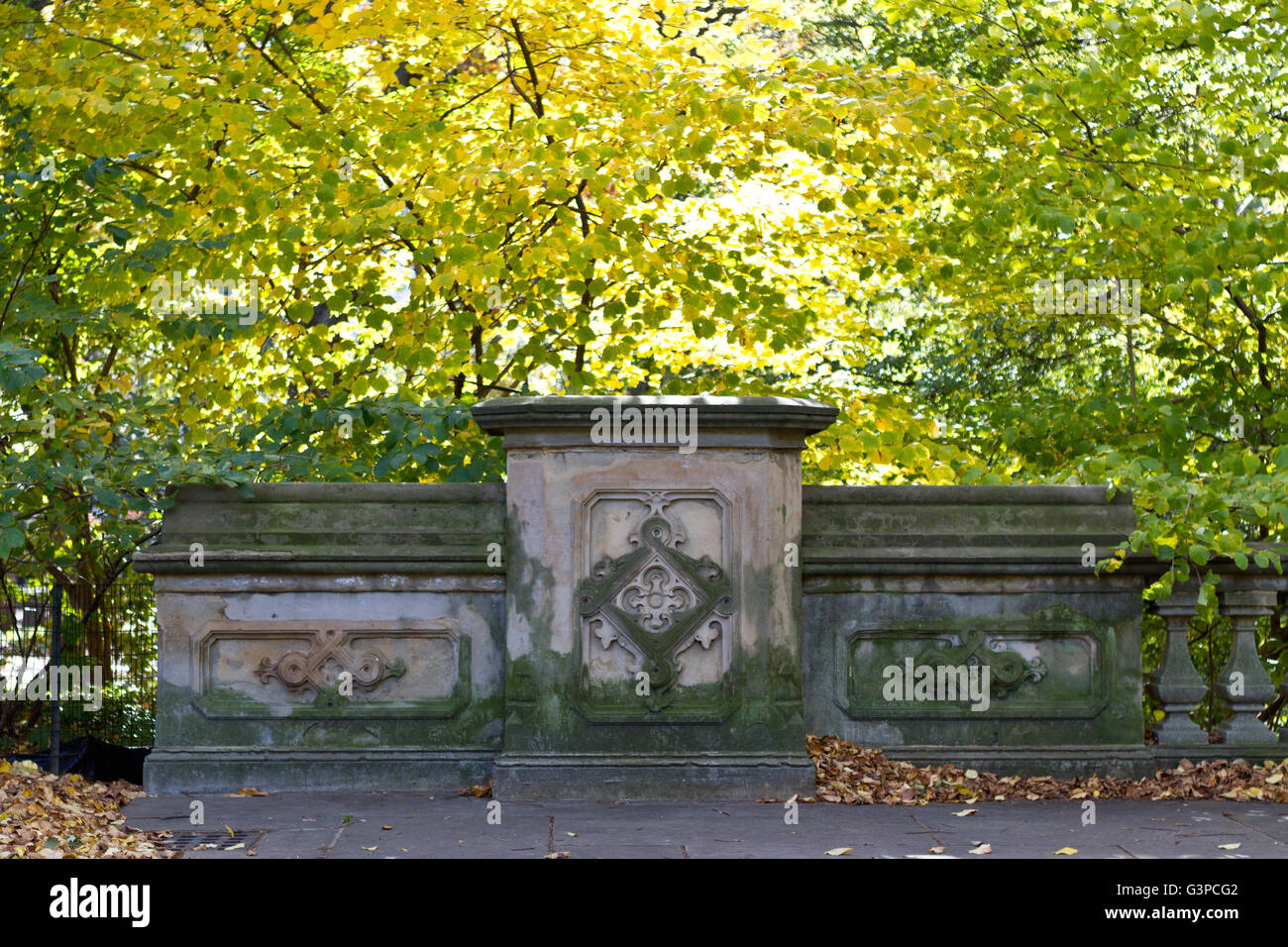 Architektonisches Detail von einer Fußgängerbrücke mit grüner Patina umgeben von Herbstlaub im Central Park Stockfoto