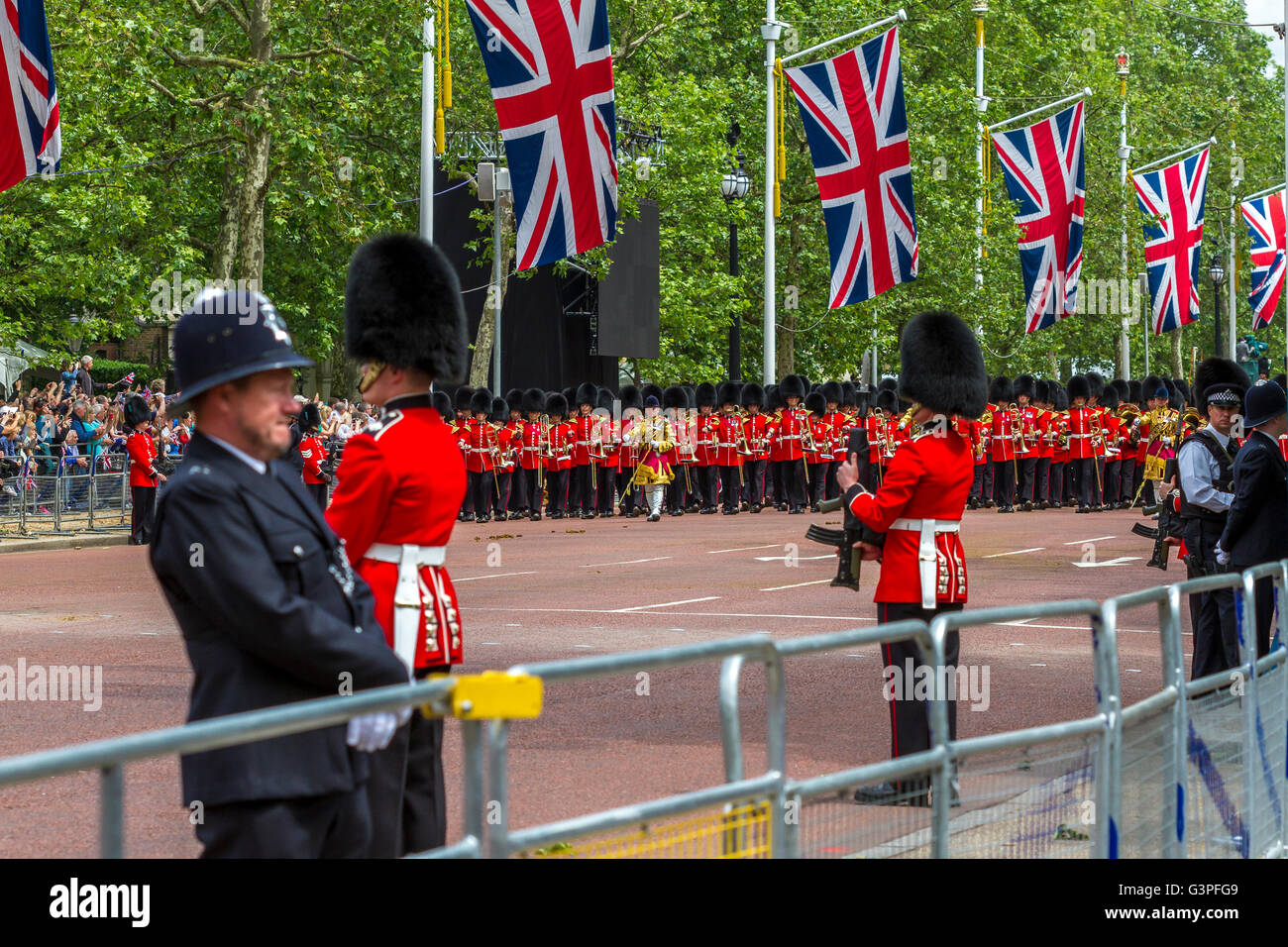 Ein Polizist wacht über die Massen, während die massierten Bands der Gardeabteilung entlang der Mall in Trooping the Color, London, Großbritannien, marschieren Stockfoto