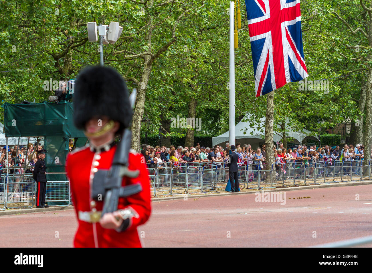 Die Union Jack-Fahne hängt an einem Fahnenmast auf der Mall in London, als ein Soldat der Coldstream Guards an der Mall in London vorbeimarschiert Stockfoto