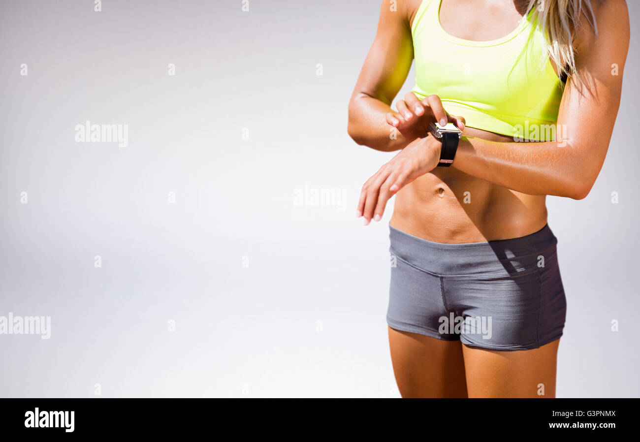 Zusammengesetztes Bild der sportliche Frau, die ihre Uhr Stockfoto