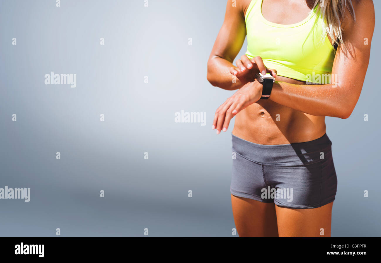Zusammengesetztes Bild der sportliche Frau, die ihre Uhr Stockfoto