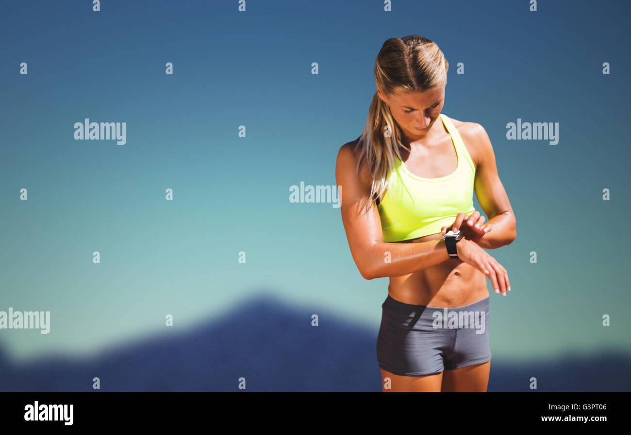 Zusammengesetztes Bild der sportliche Frau, die ihre Uhr Stockfoto
