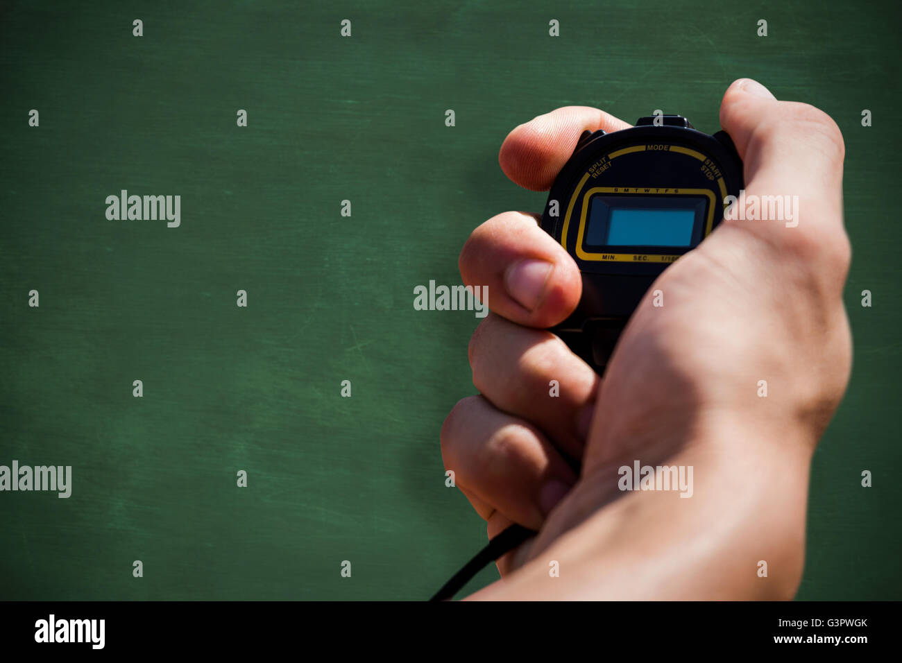 Nahaufnahme von Hand mit einem Chronometer gegen grüne Tafel Stockfoto
