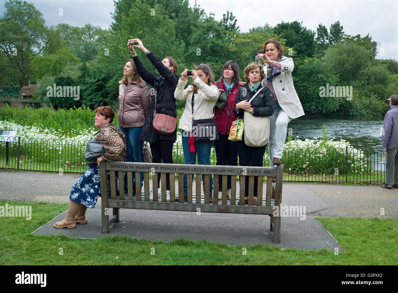 Eine Gruppe von weiblichen Touristen stehen auf einer Parkbank in St James Park gerade eine Parade vorbei gehen. Stockfoto