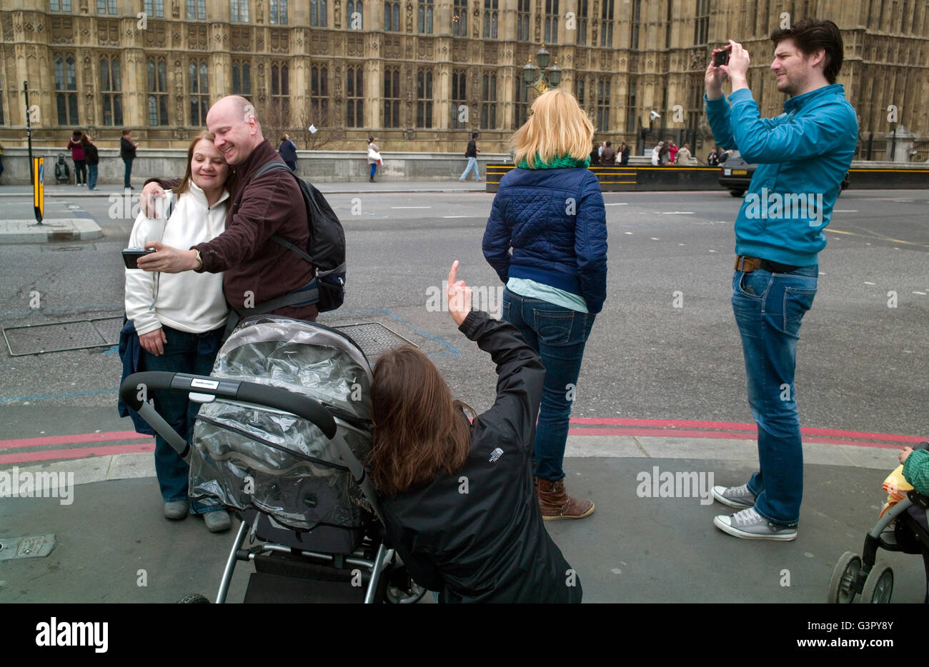 Eine Gruppe von Touristen stehen an der Ecke der Brücke Straße Westminster unter Schnappschüsse und Selfies. Stockfoto
