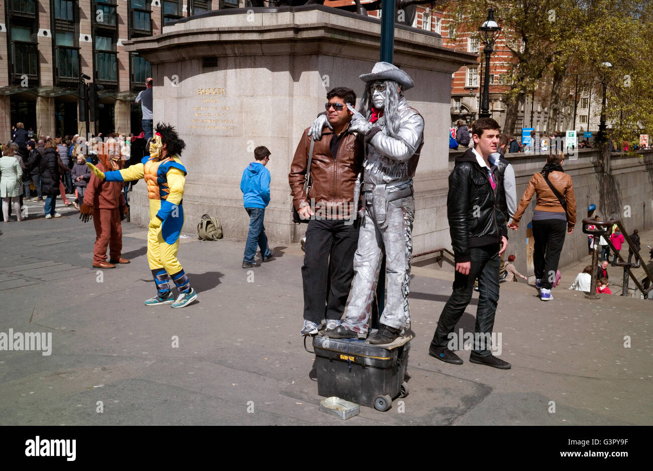Ein Tourist posiert auf Westminster Bridge mit einem Mann gekleidet als Silber Cowboy stehend auf einer Kunststoff-Box zeigt. Stockfoto
