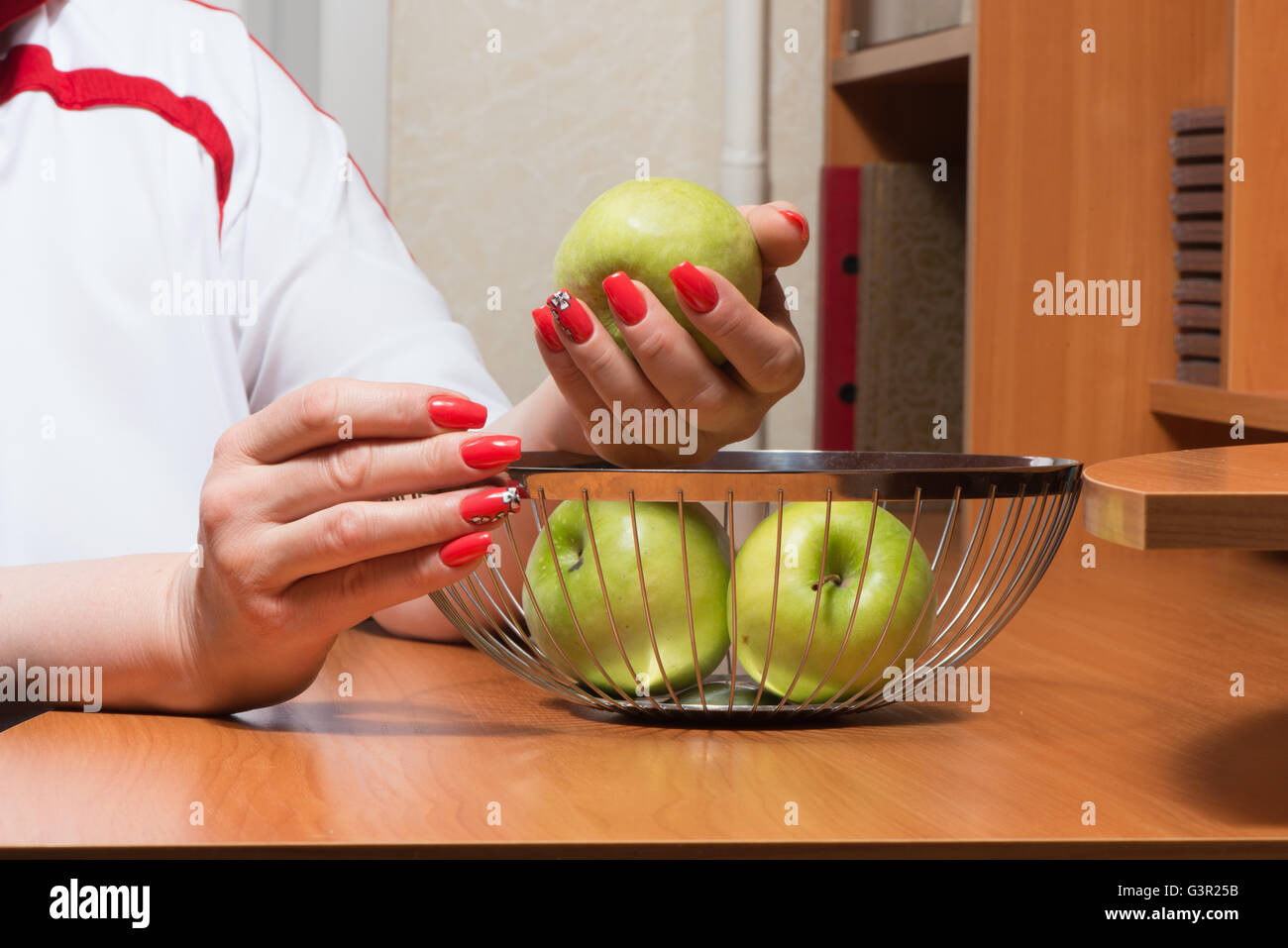 Weibliche Hände mit Maniküre bekommen Äpfel aus einem Korb Stockfoto