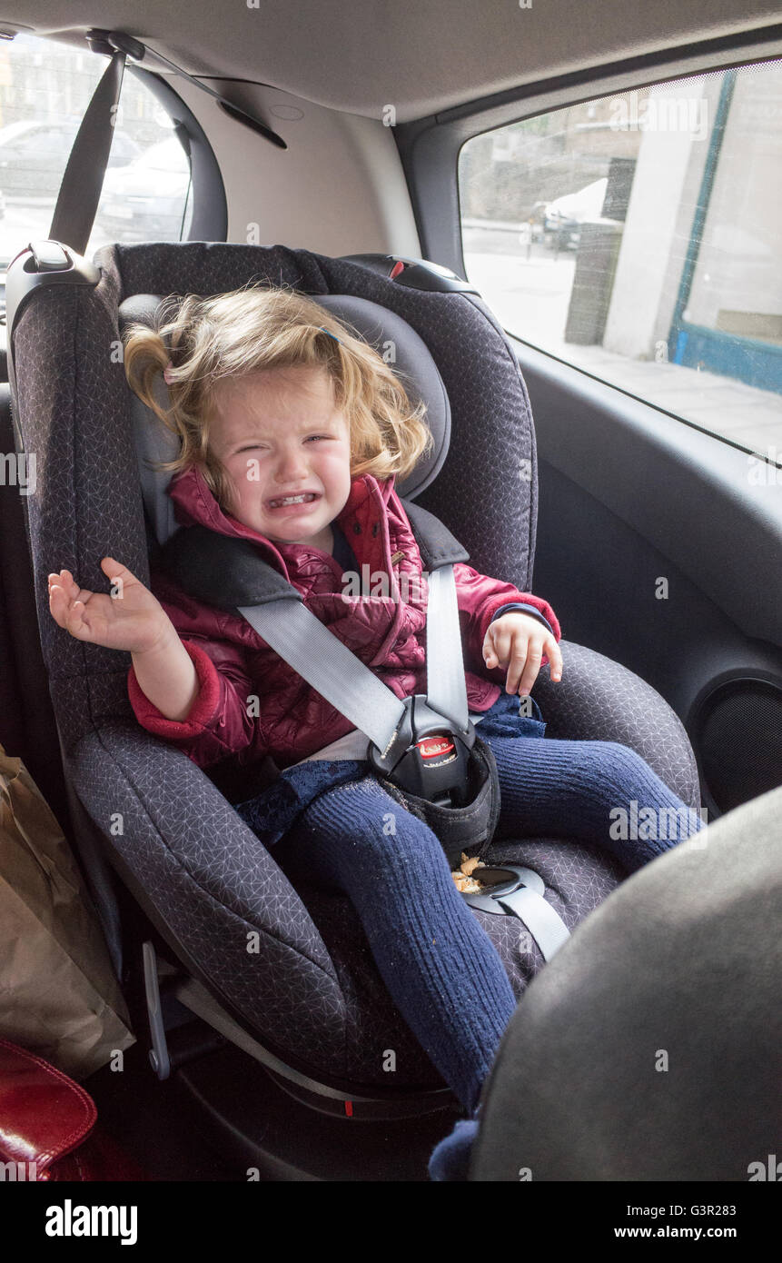 Zwei Jahre altes Kleinkind weinend in ihrem Autositz, England, UK Stockfoto