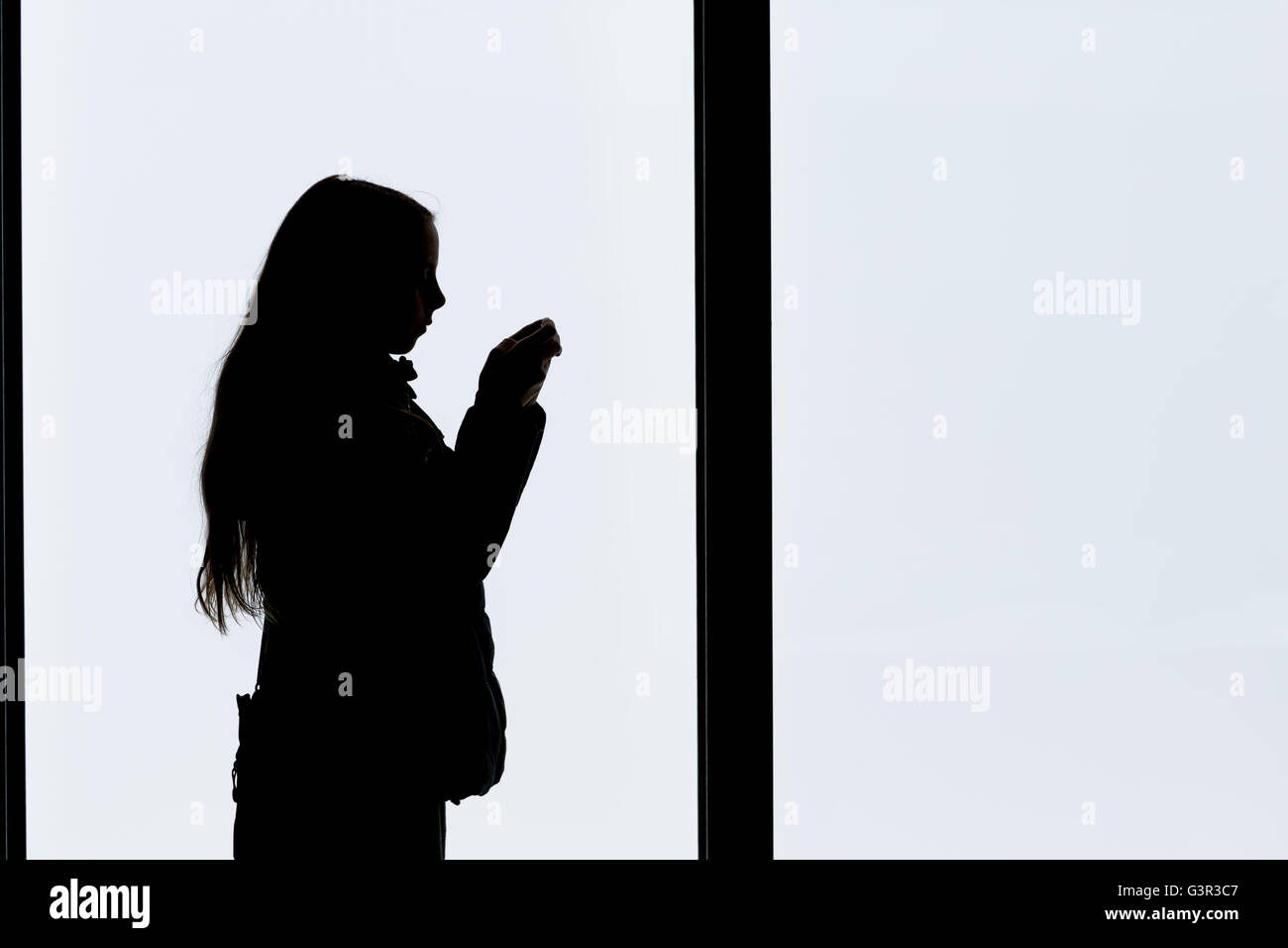 Silhouette eines Mädchens im Profil Blick auf ihr Handy Stockfoto