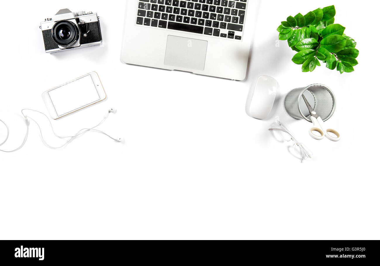 Arbeitsplatz mit Laptop, Handy, Notebook, Fotoapparat, grüne Pflanze. Büro Schreibtisch weiß Hintergrund. Held-header Stockfoto