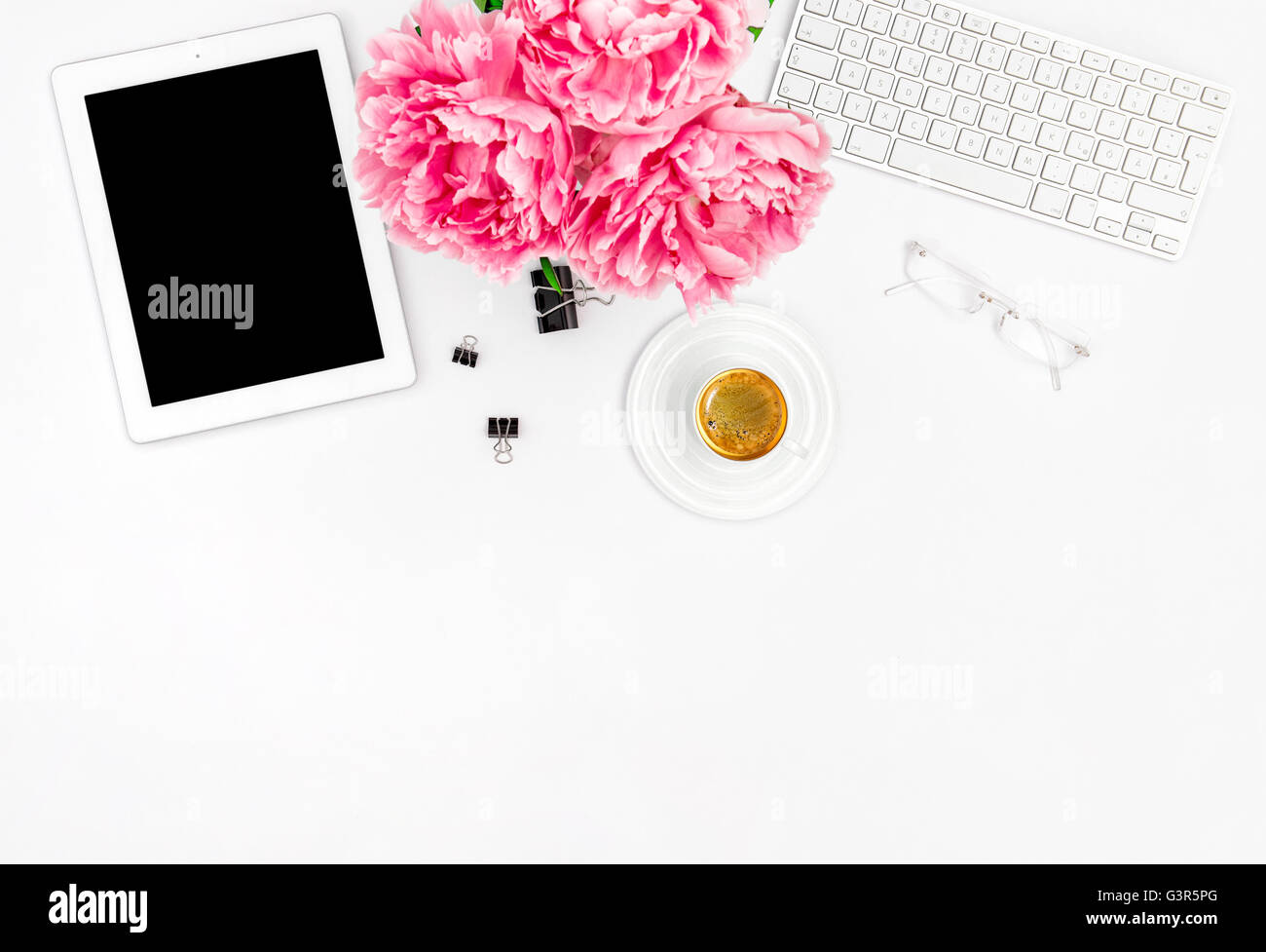 Feminine Büroarbeitsplatz mit Kaffee und Blumen. Mock-up mit digitalen Tablet PC. Wohnung für social-Media-Blogger legen Stockfoto