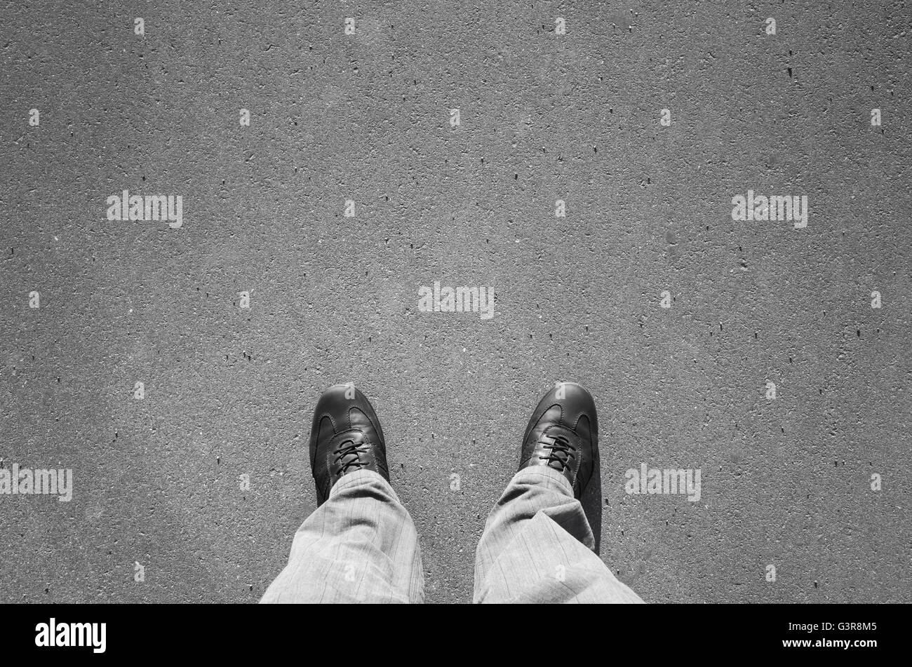 Männliche Füße in schwarz neu glänzende Lederschuhe stehend auf städtischen Asphaltdecke Stockfoto