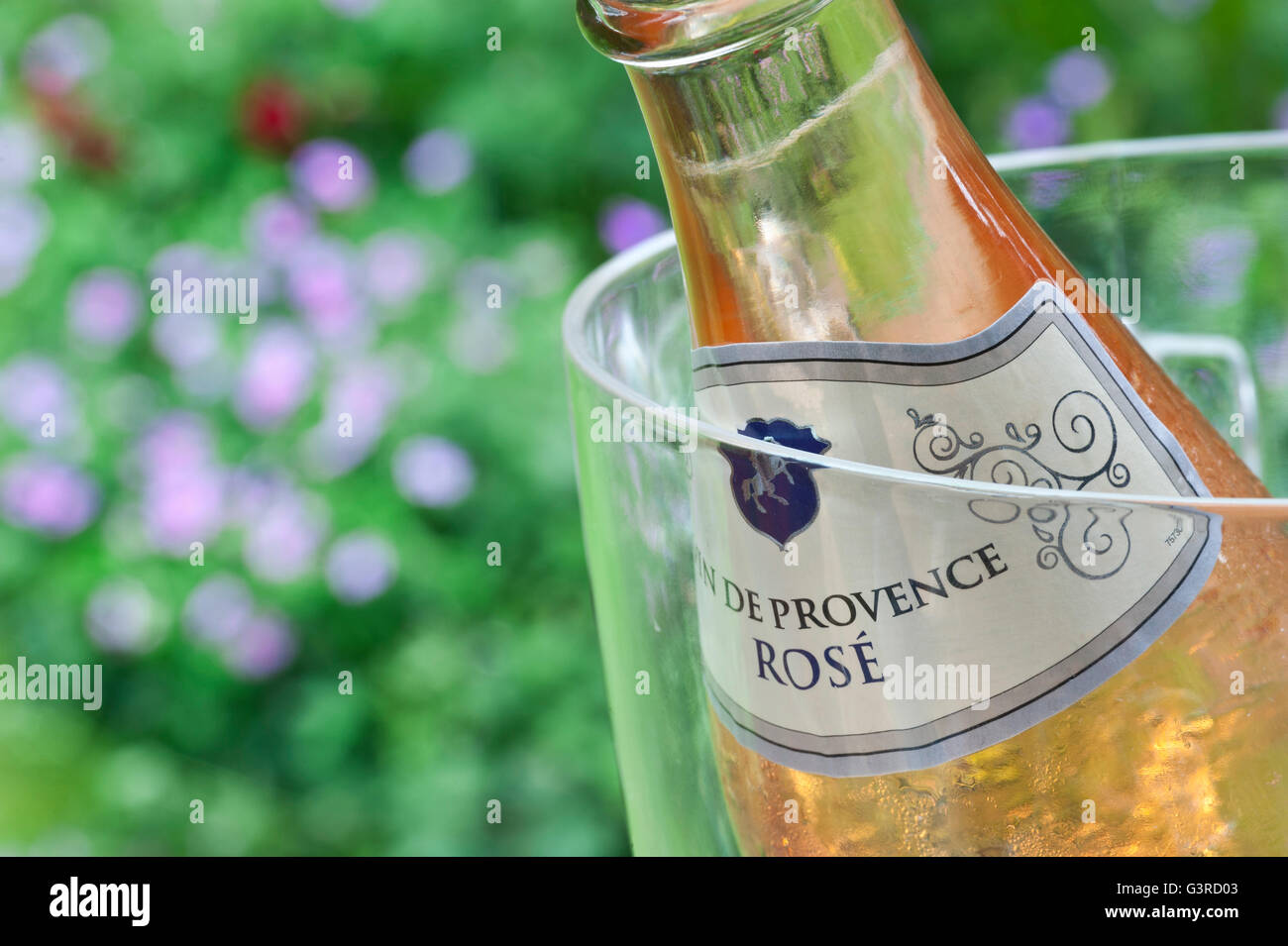 Schließen Sie die Ansicht auf Cotes de Provence französische Rosé Wein Flasche im Weinkühler auf alfresco Picknick-Tisch mit Blumen hinter bei Sonnenuntergang Stockfoto