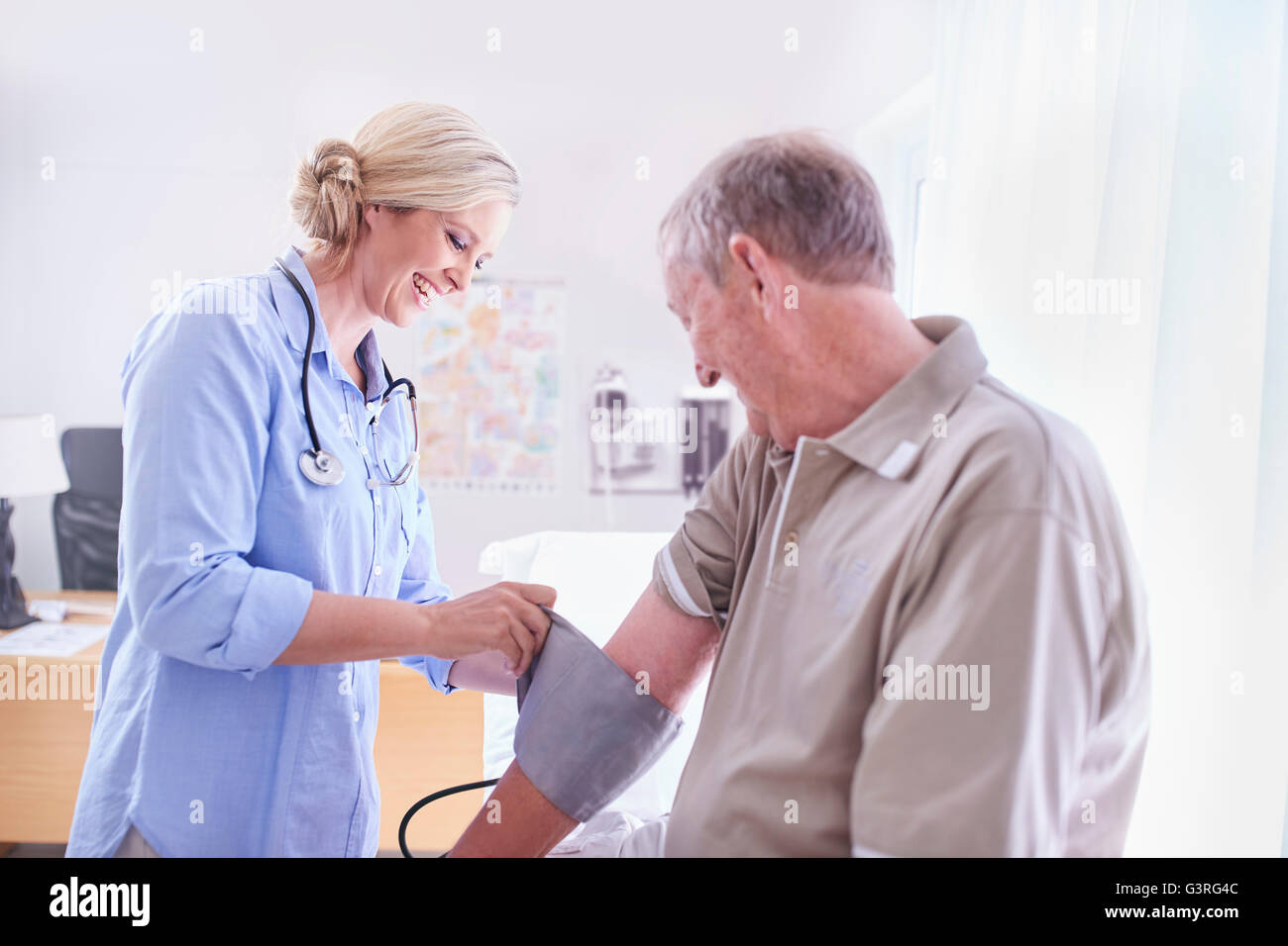 Arzt überprüft senior woman Blutdruck im Untersuchungsraum Stockfoto