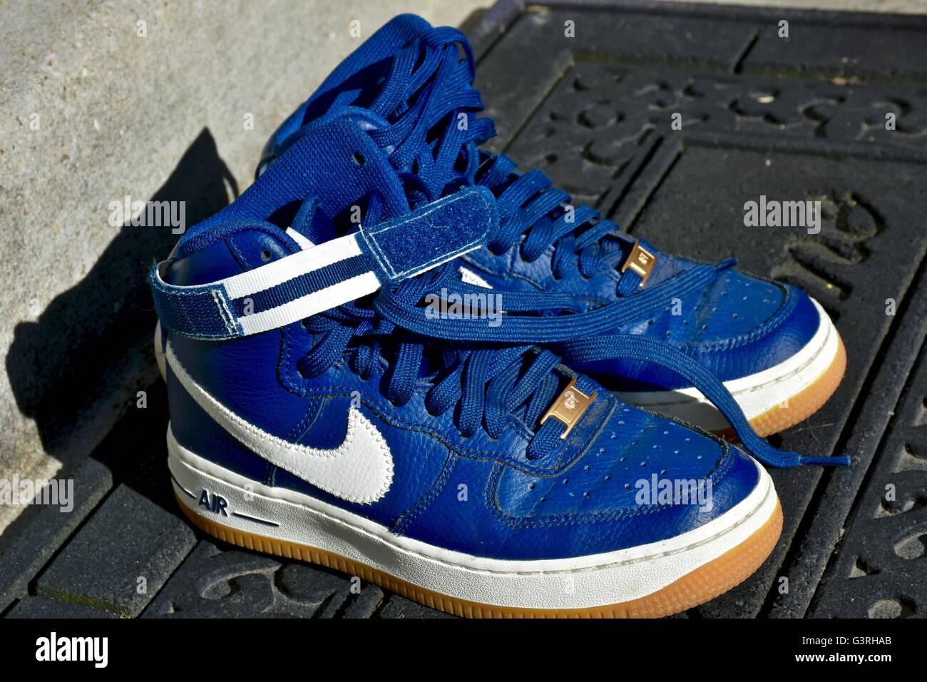 Ein paar blaue Nike Schuhe sitzen auf einer Fußmatte vor einem Haus Stockfoto