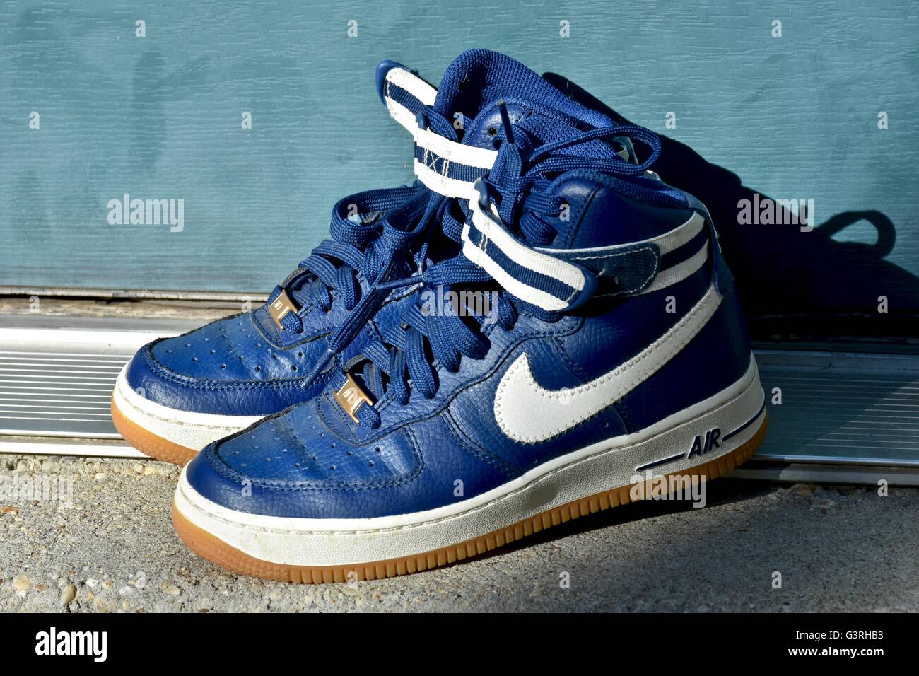 Ein paar blaue Nike Schuhe sitzen auf einer Fußmatte vor einem Haus Stockfoto