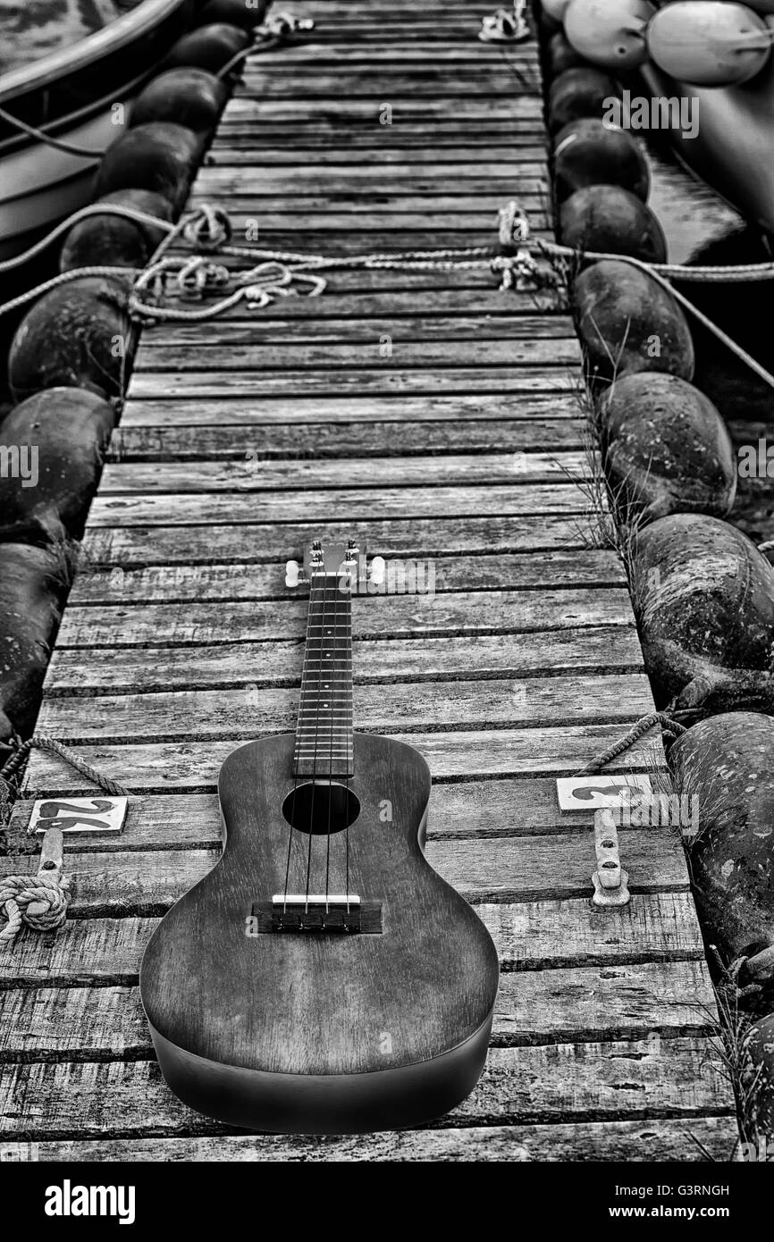 Akustische Gitarre auf einem Lattenrost aus Holz Bootsliegeplatz Stockfoto