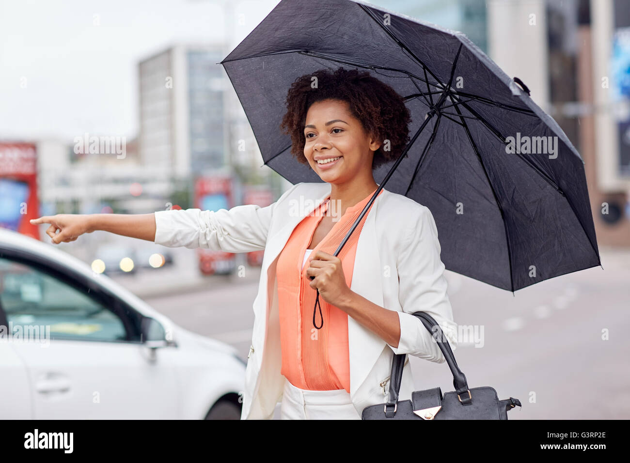 glücklich afrikanische Frau mit Regenschirm Fang taxi Stockfoto